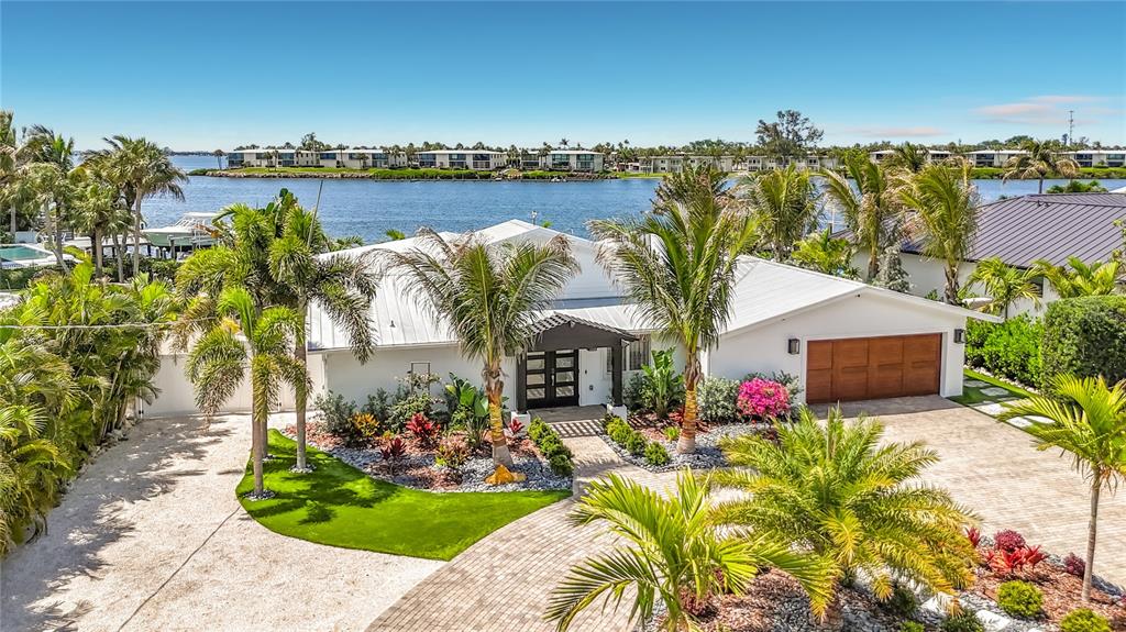 An exterior view of a white waterfront house with a paved driveway and palm trees — 605 KEY ROYALE DRIVE, HOLMES BEACH, FL