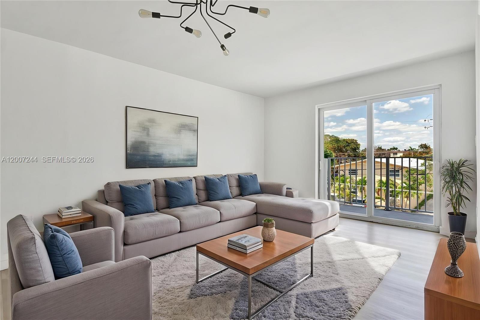 A living room features a gray sectional sofa, a wooden coffee table, and a balcony view — 620 SW 10th St # 301, Miami FL 33130, MIAMI, FL