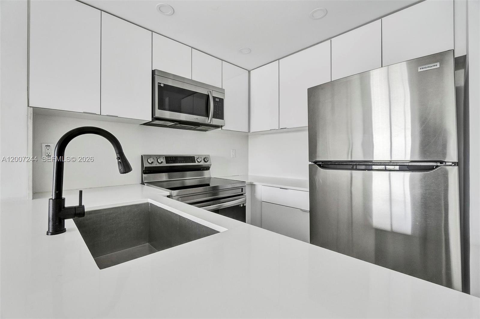 A modern kitchen features white cabinetry, stainless steel appliances, and a black faucet — 620 SW 10th St # 301, Miami FL 33130, MIAMI, FL