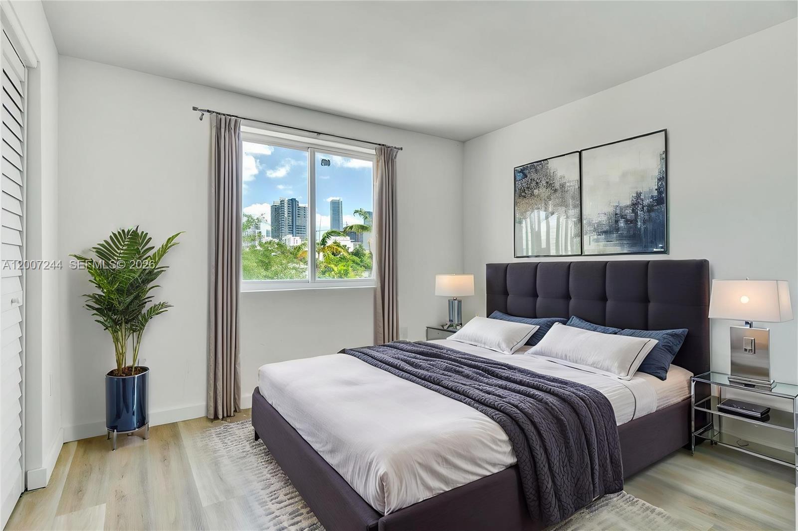 A modern bedroom features a dark upholstered bed, two bedside lamps, and a city view — 620 SW 10th St # 301, Miami FL 33130, MIAMI, FL