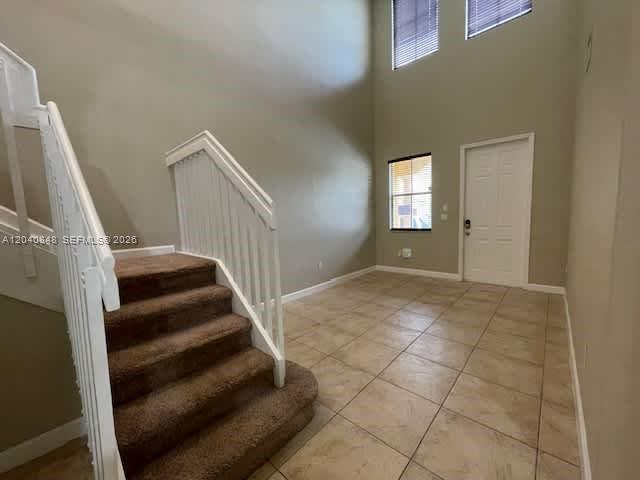 An entryway features a carpeted staircase with a white railing and light-colored tile flooring — MIAMI, FL