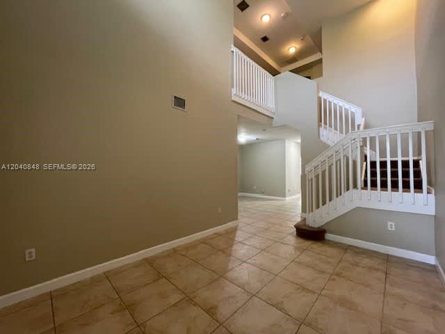 An interior view shows a tiled foyer with a staircase and a high vaulted ceiling — MIAMI, FL