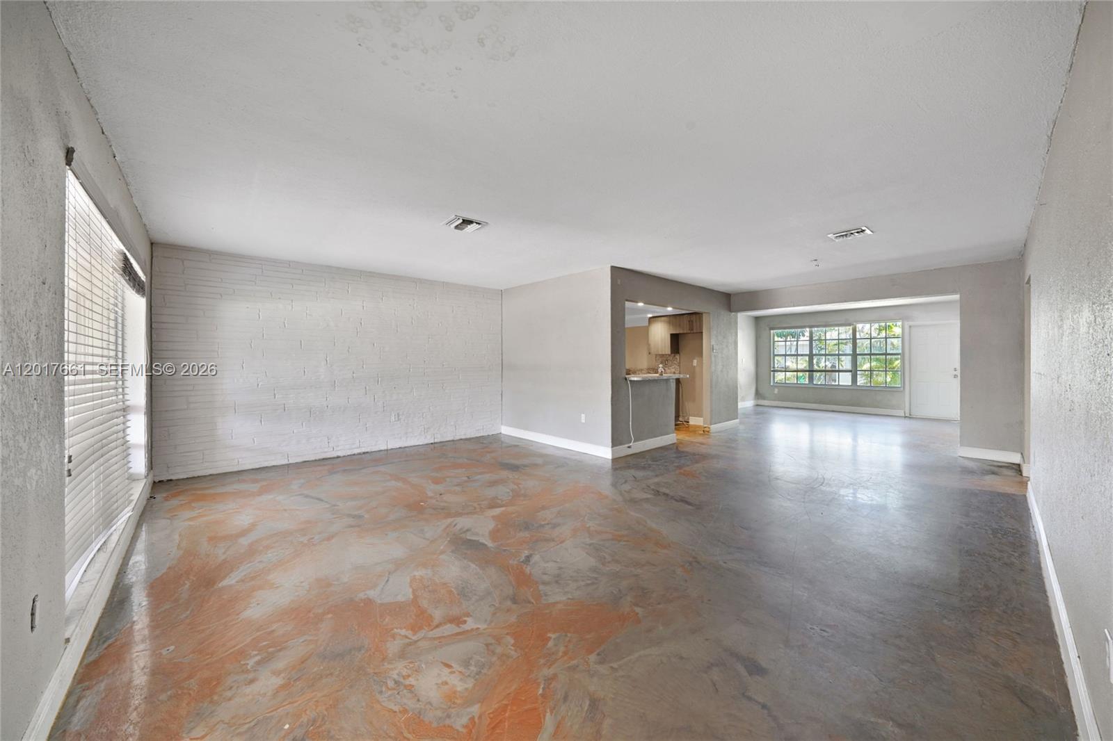 An open-concept living area features a white brick wall and polished concrete flooring — 7773 Biltmore Blvd, Miramar FL 33023, MIRAMAR, FL