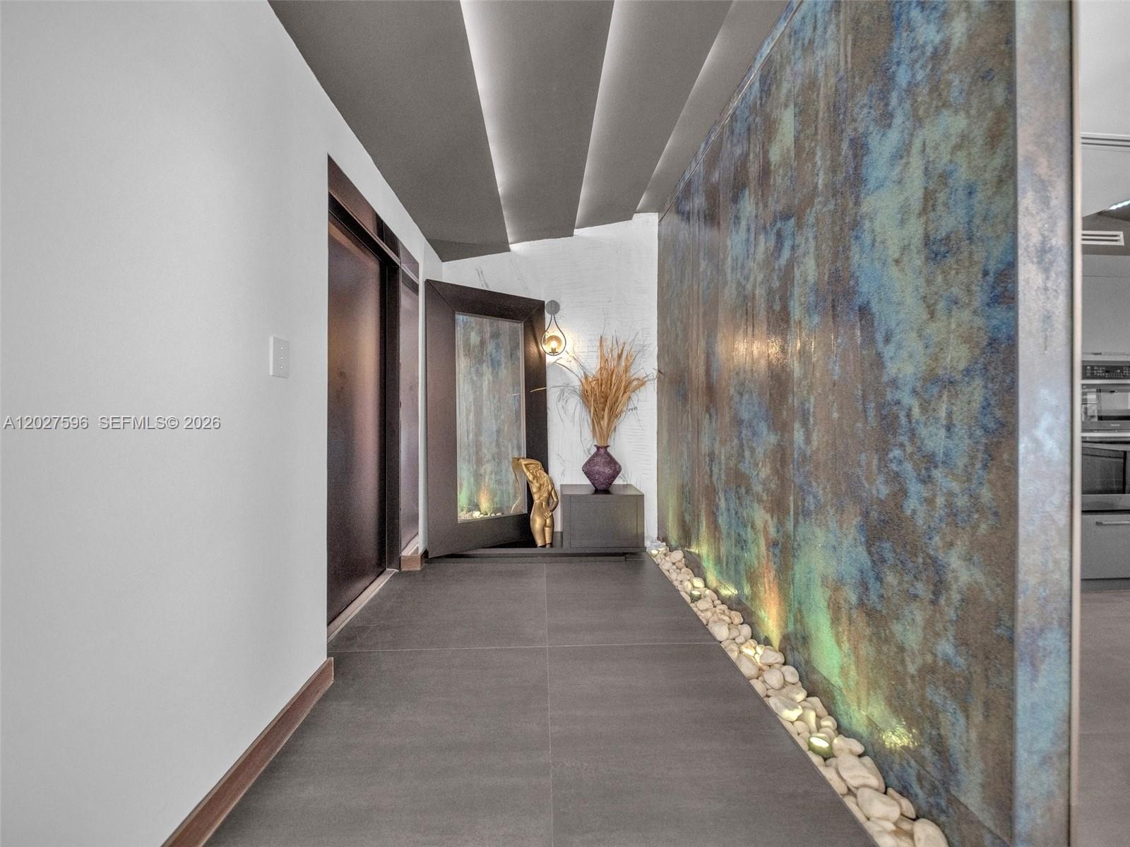 A hallway features a textured blue accent wall, stone floor, and a decorative water feature — 1141 Adams St, Hollywood FL 33019, HOLLYWOOD, FL