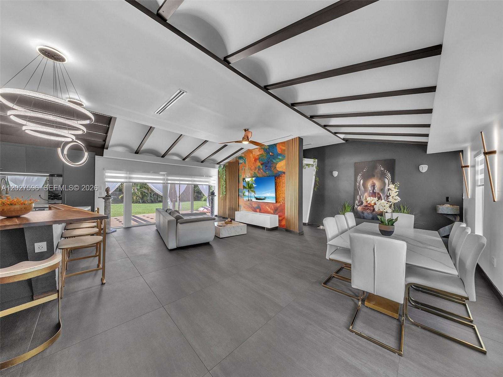 A modern open-concept living and dining area features dark tile floors and exposed ceiling beams — 1141 Adams St, Hollywood FL 33019, HOLLYWOOD, FL