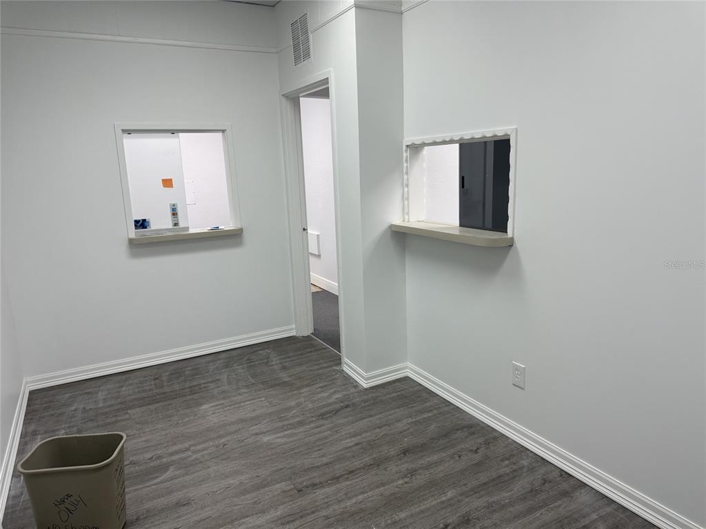 An office room features light gray walls, wood-look flooring, and two service windows — 501 S LINCOLN AVENUE UNIT 22, CLEARWATER, FL