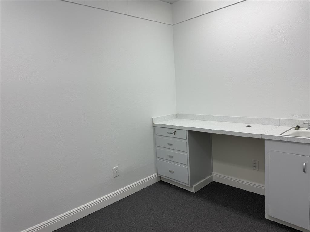 A small room features a built-in desk with drawers, a sink, and gray carpet — 501 S LINCOLN AVENUE UNIT 22, CLEARWATER, FL