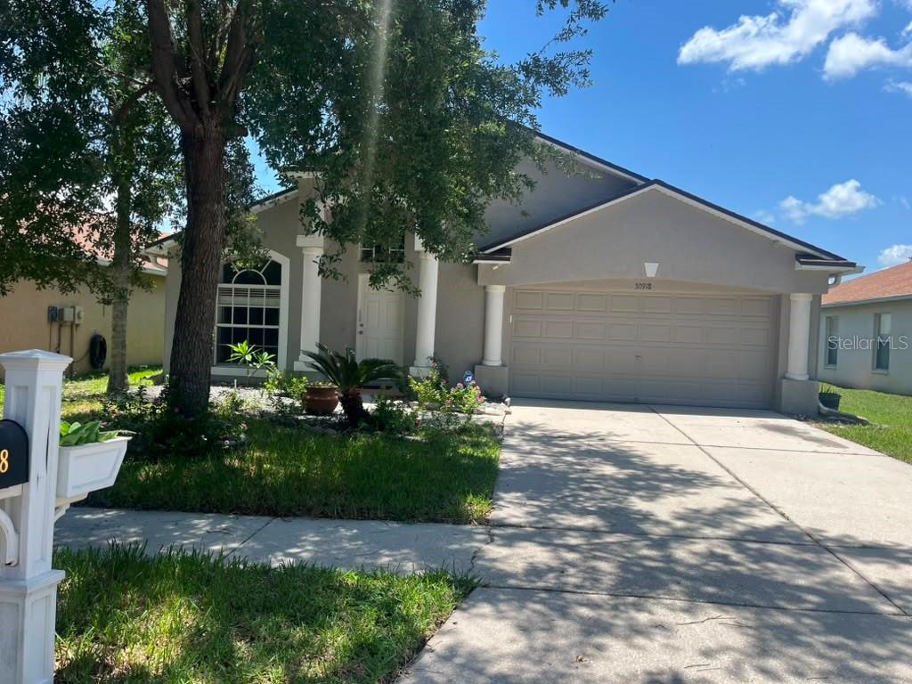 A single-story house with a gray exterior, a two-car garage, and a concrete driveway — 30918 STONE ARCH AVENUE, WESLEY CHAPEL, FL