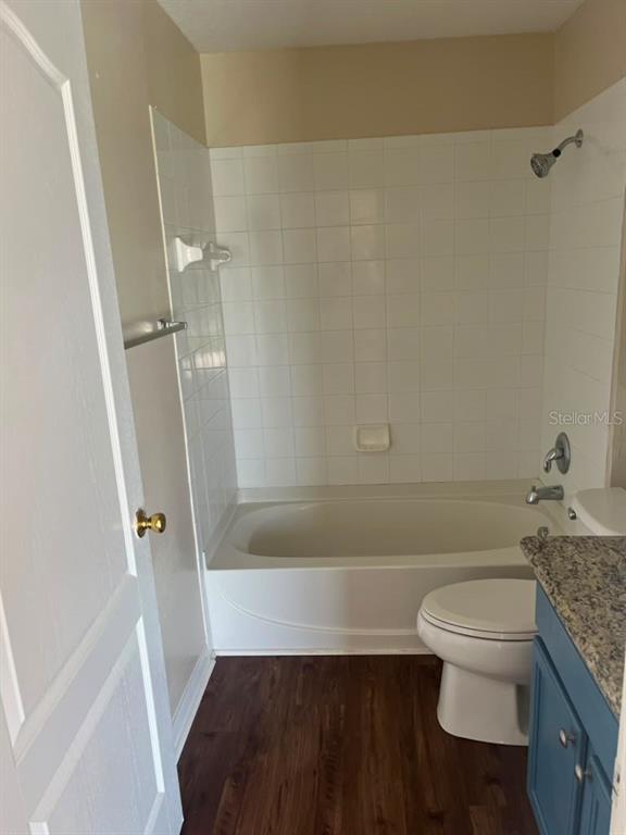 A bathroom features a white bathtub with a tiled surround, a toilet, and a vanity — 30918 STONE ARCH AVENUE, WESLEY CHAPEL, FL