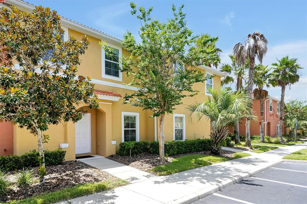 A two-story yellow townhouse with a white front door and surrounding landscaping — 3008 RED GINGER ROAD UNIT 3008, KISSIMMEE, FL