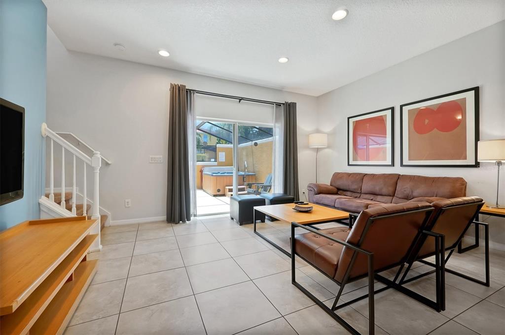 A living room features tile floors, a brown leather sofa, and a sliding glass door — 3008 RED GINGER ROAD UNIT 3008, KISSIMMEE, FL