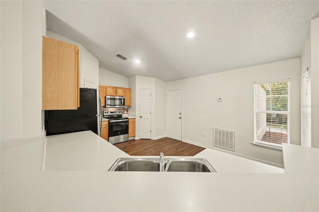 A kitchen with light wood cabinets, stainless steel appliances, and a double-basin sink — 909 BRISTLE CONE COURT, MINNEOLA, FL