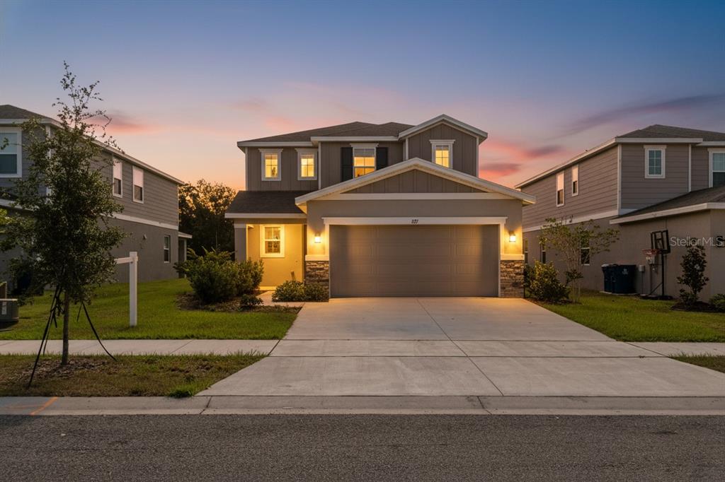 A two-story suburban house with a two-car garage at dusk — 821 BLUE CREEK DRIVE, HAINES CITY, FL