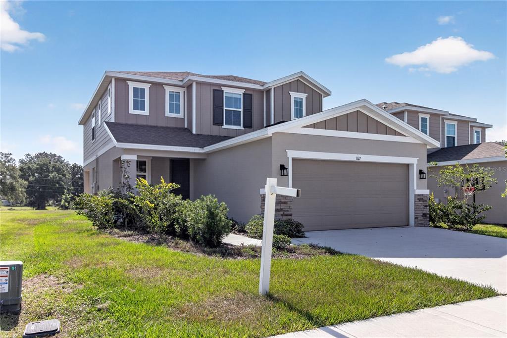 A two-story suburban house with a beige stucco exterior, brown siding, and a two-car garage — 821 BLUE CREEK DRIVE, HAINES CITY, FL