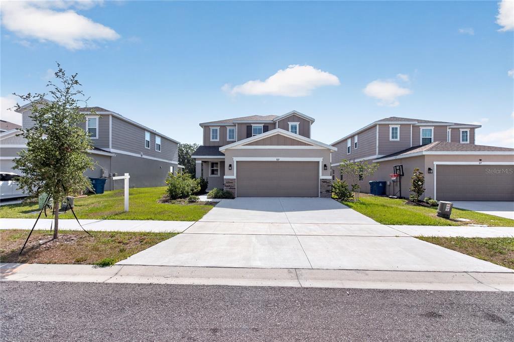 A two-story suburban house with a tan exterior and a two-car garage — 821 BLUE CREEK DRIVE, HAINES CITY, FL
