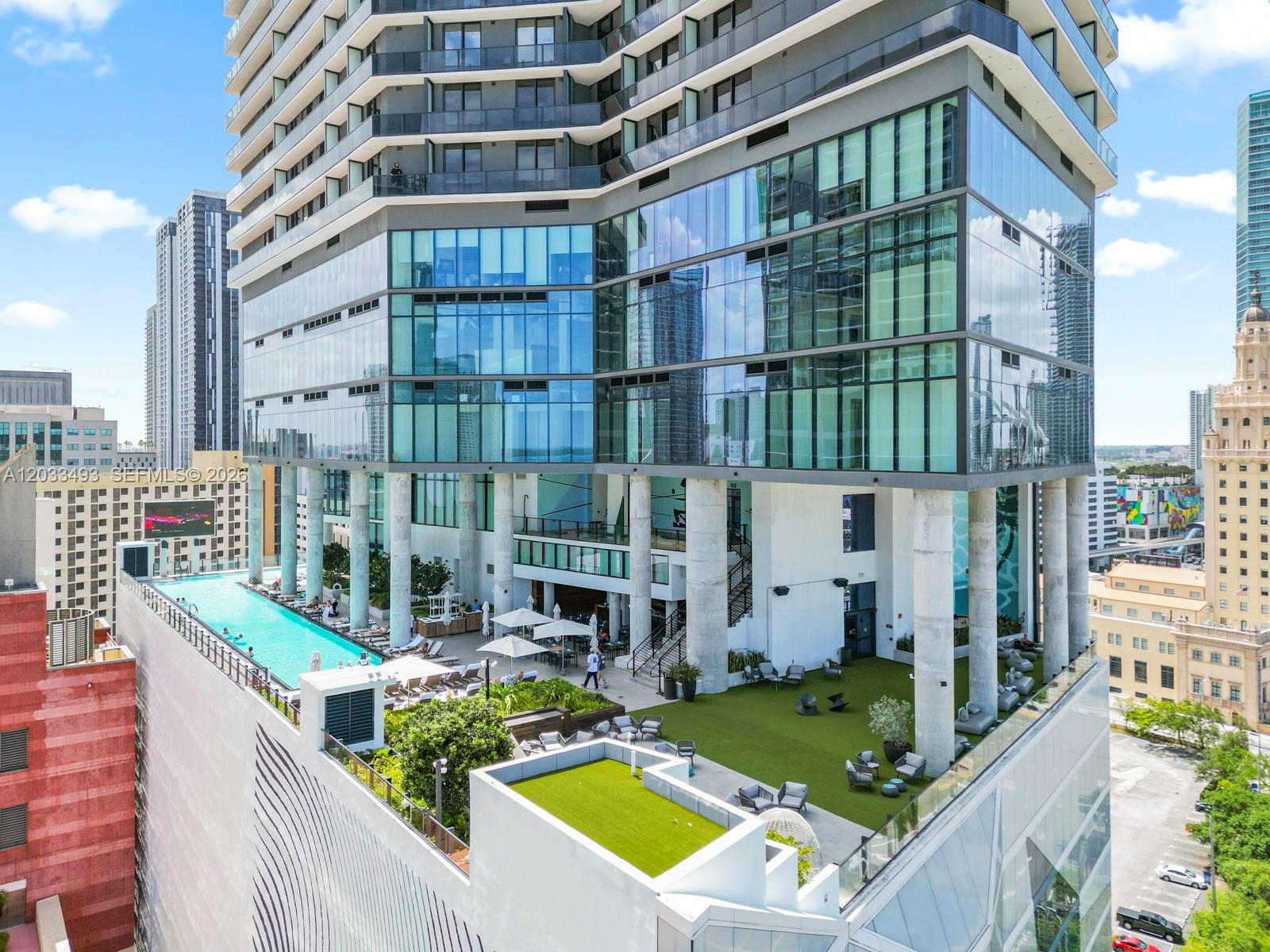 An elevated outdoor terrace features a swimming pool, lounge seating, and artificial turf under a skyscraper — 398 NE 5th St # 3318, Miami FL 33132, MIAMI, FL