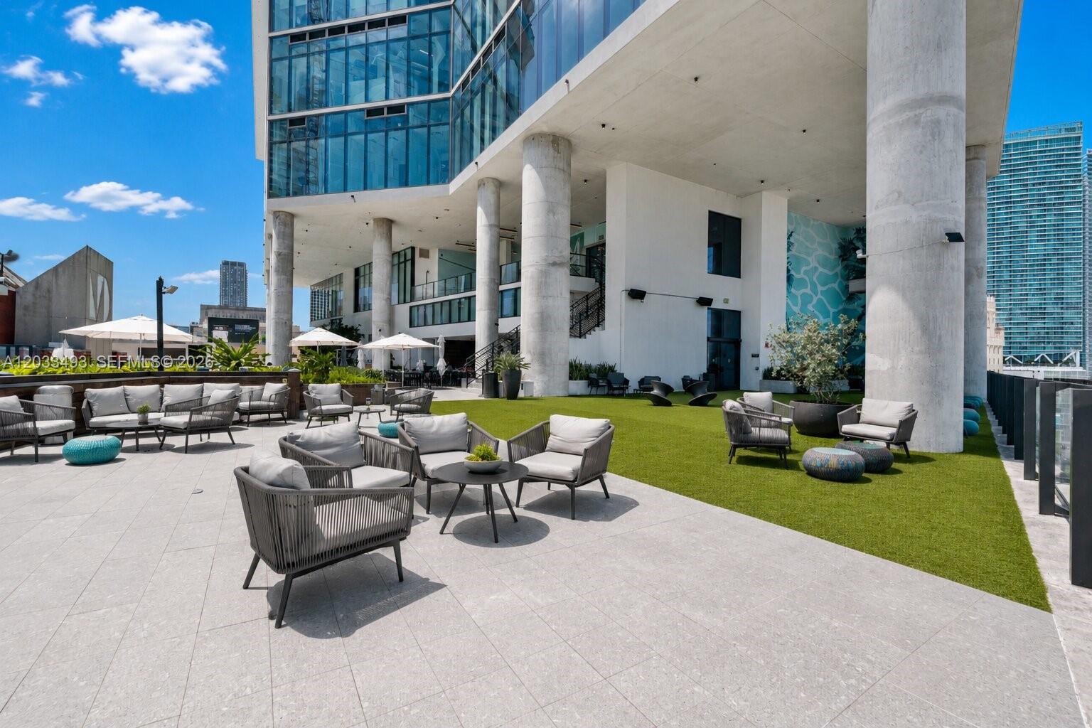 An outdoor terrace features patio furniture on a tiled patio and a green lawn area — 398 NE 5th St # 3318, Miami FL 33132, MIAMI, FL