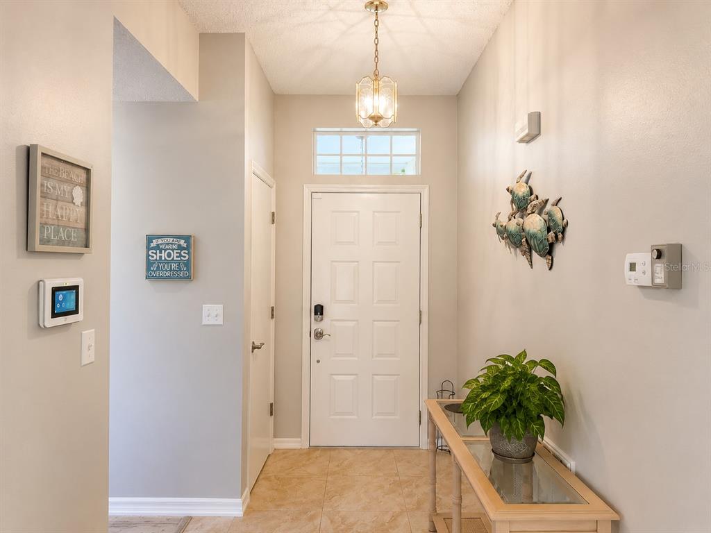 A kitchen with wood cabinets, stainless steel appliances, and tile flooring opens to a dining area — 822 MCCALLISTER AVENUE UNIT 822, SUN CITY CENTER, FL