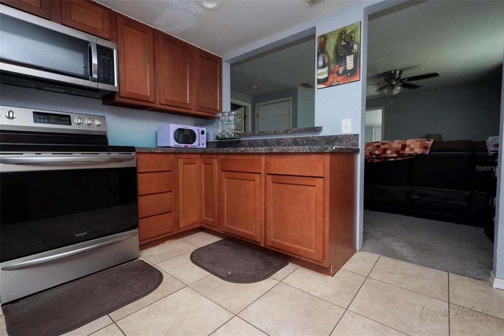 A kitchen features wood cabinets, stainless steel appliances, and tile flooring — 1132 CARLTON STREET, CLEARWATER, FL