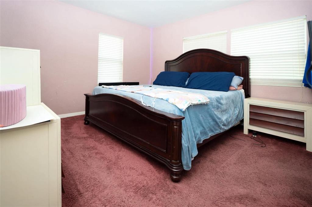 A bedroom features a dark wood bed frame, blue bedding, and pink carpeting — 1132 CARLTON STREET, CLEARWATER, FL