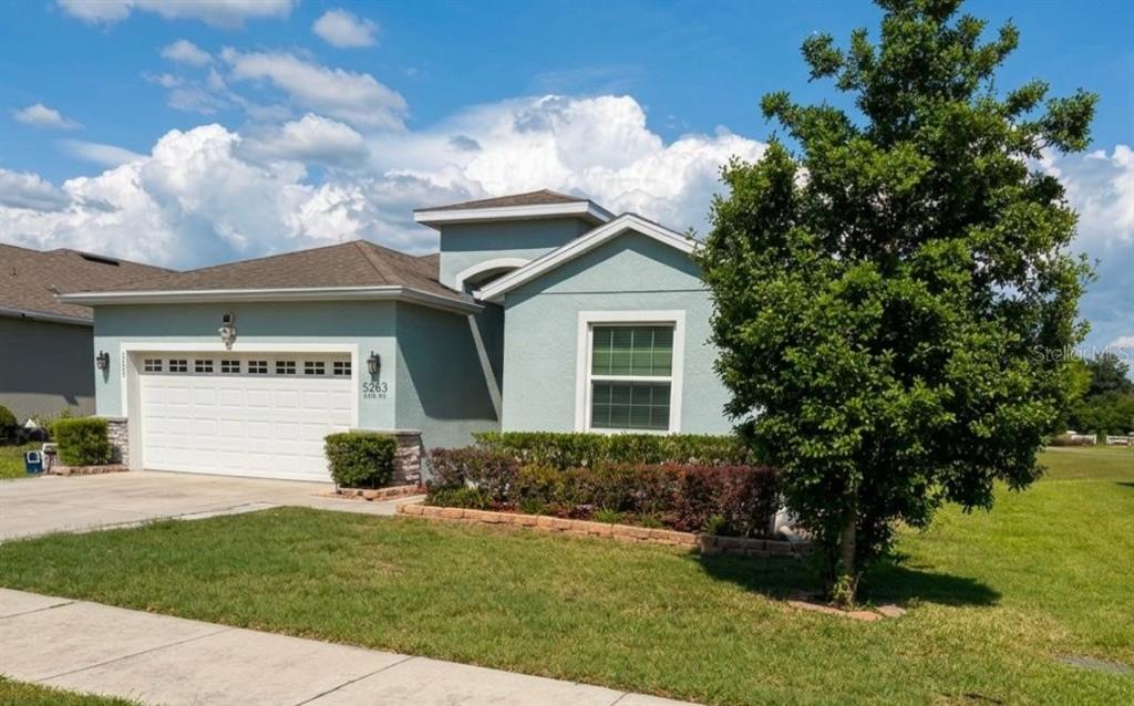 A light blue single-story house with a two-car garage and a large front tree — 5703 SW 50TH AVENUE, OCALA, FL