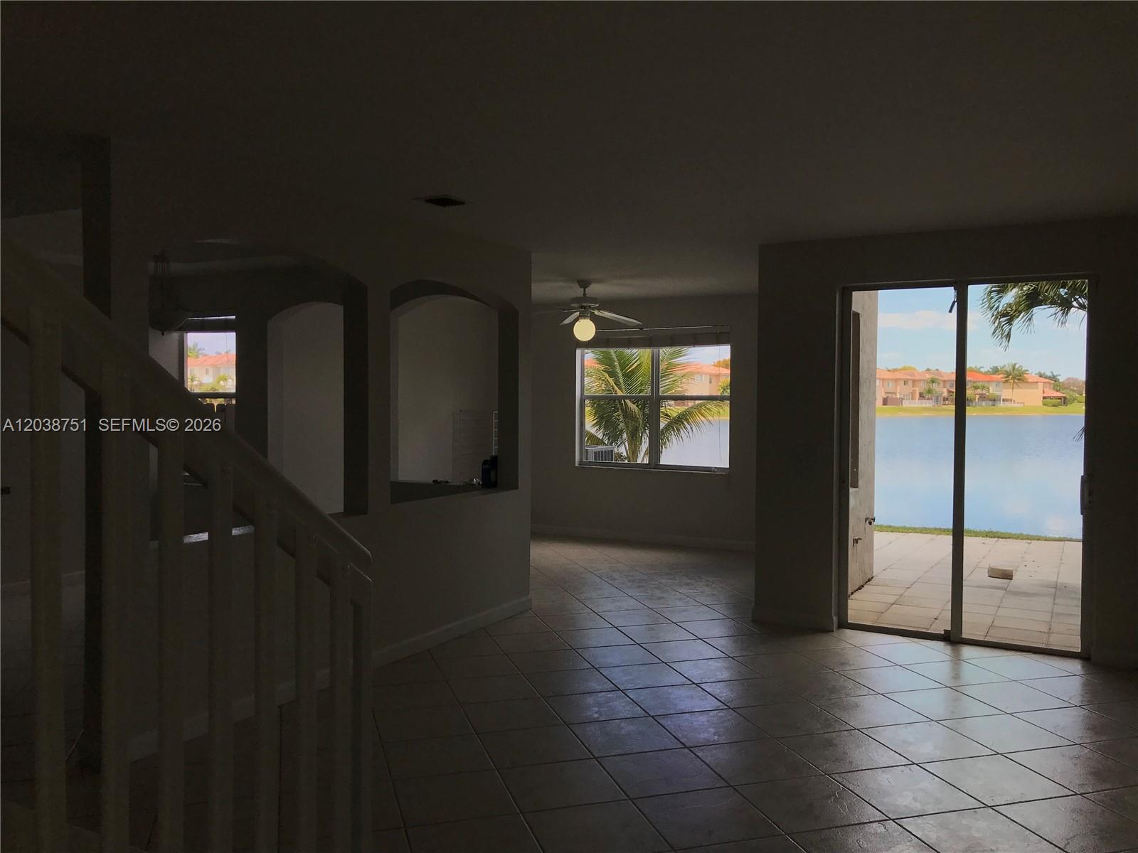 An interior view shows a tiled living area with arched openings and a lake view — 6674 NW 107th Pl, Doral FL 33178, DORAL, FL