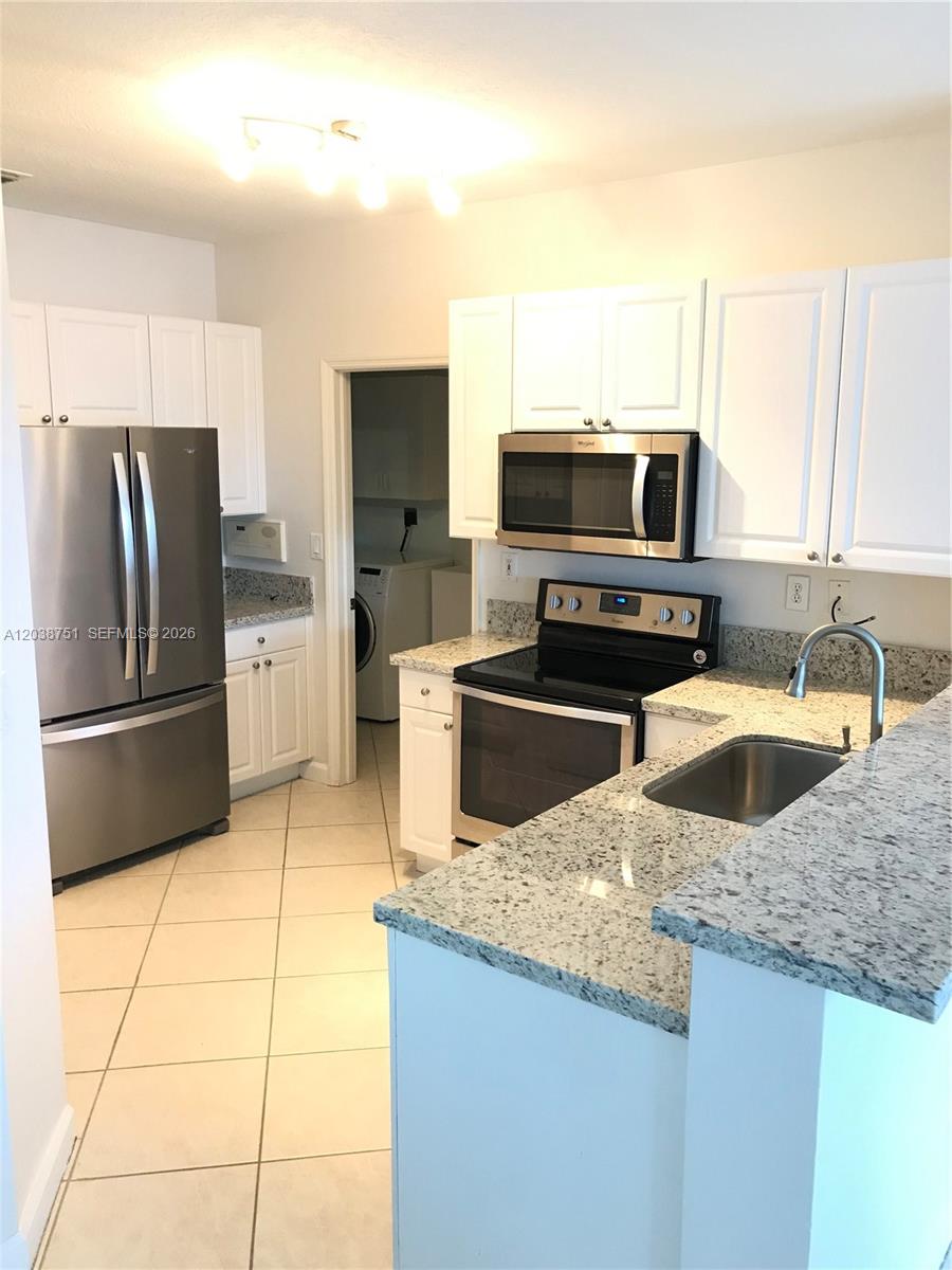 A kitchen features white cabinets, granite countertops, stainless steel appliances, and tile flooring — 6674 NW 107th Pl, Doral FL 33178, DORAL, FL