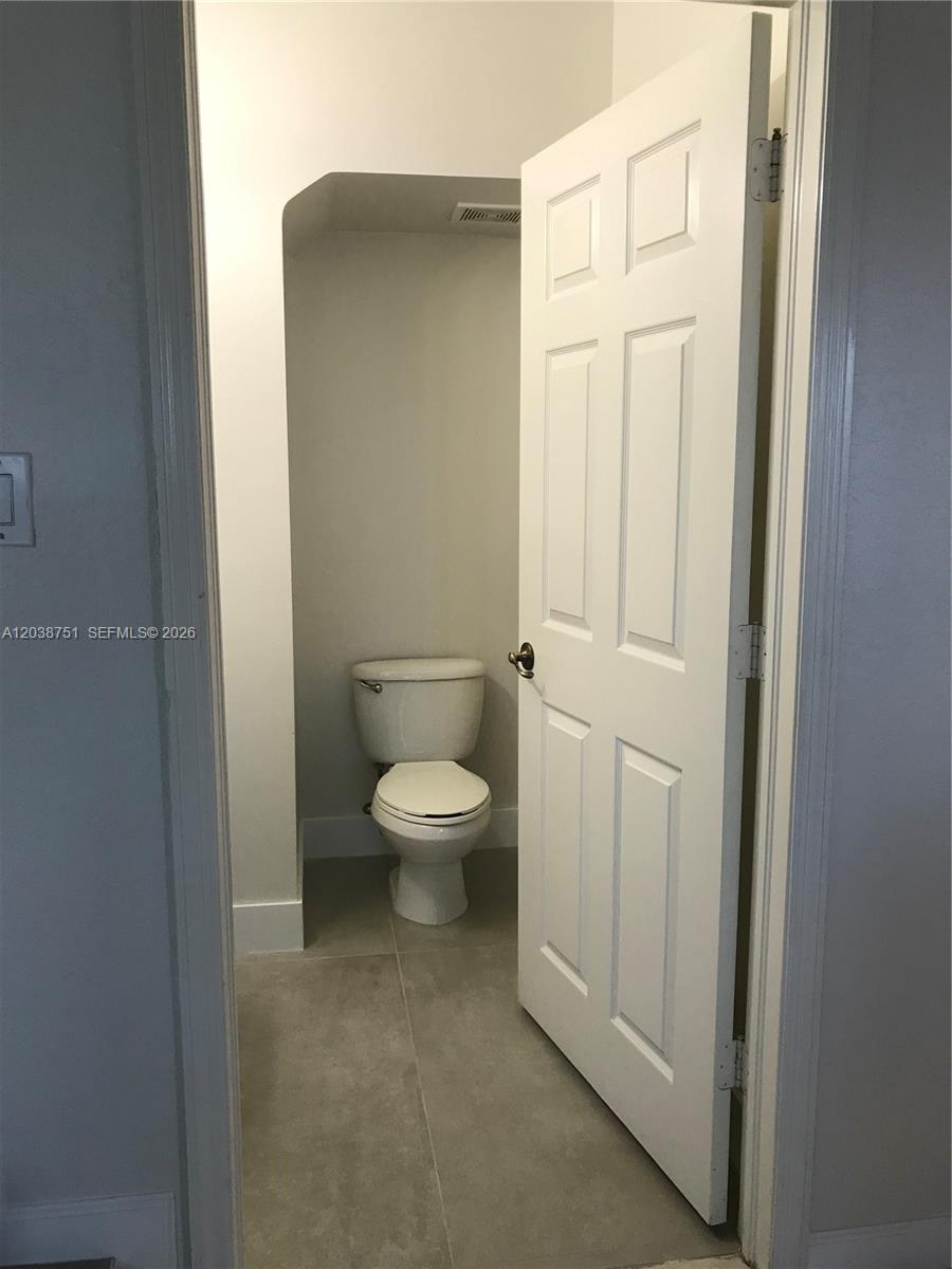 A small, enclosed toilet room features light-colored walls and neutral floor tiles — 6674 NW 107th Pl, Doral FL 33178, DORAL, FL
