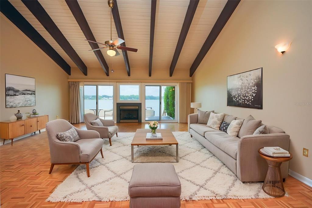 A living room features a vaulted ceiling with exposed beams, a fireplace, and lake views — 9 CASA LOMA WAY UNIT 9, LAKELAND, FL