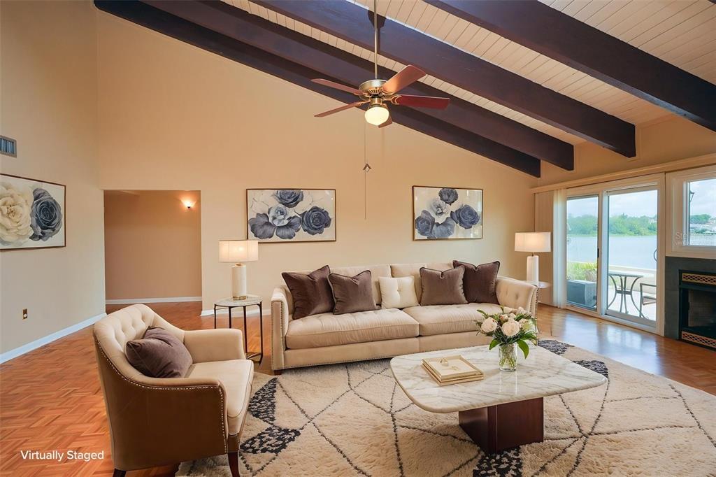 A living room with vaulted ceilings, exposed beams, a fireplace, and a view of water — 9 CASA LOMA WAY UNIT 9, LAKELAND, FL