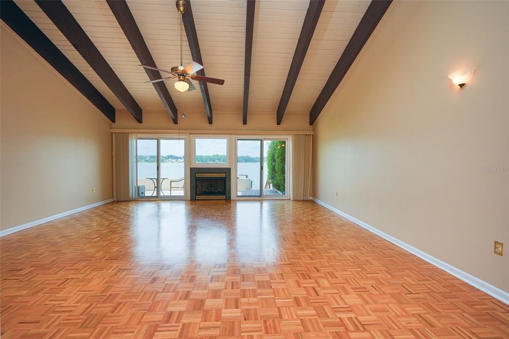 A spacious living room features a vaulted ceiling with exposed beams, parquet flooring, and a fireplace — 9 CASA LOMA WAY UNIT 9, LAKELAND, FL