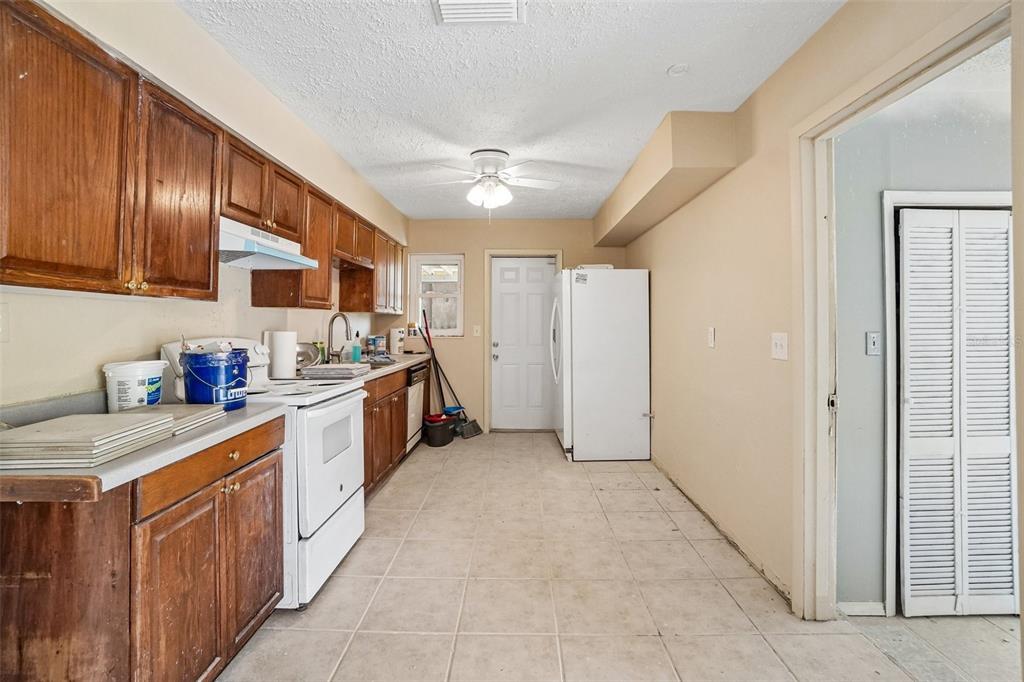 A kitchen with wood cabinets, white appliances, tile flooring, and a ceiling fan — 1090 EDGEHILL AVE, SPRING HILL, FL