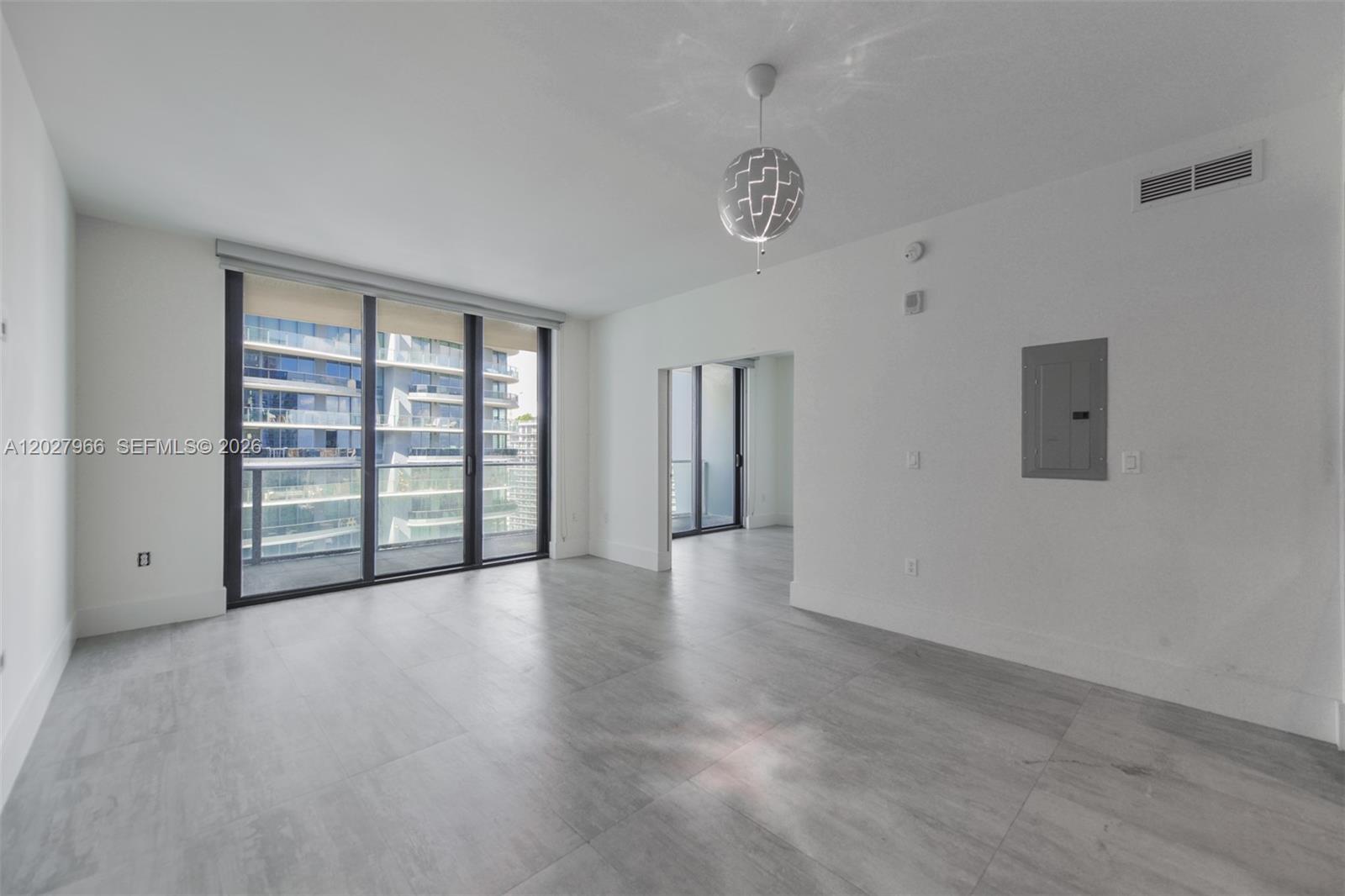 An empty room with light gray tile flooring, a modern pendant light, and floor-to-ceiling windows — 1010 Brickell Ave # 4607, Miami FL 33131, MIAMI, FL