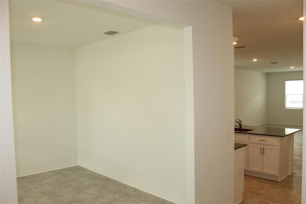 A view of a tiled dining nook adjacent to a kitchen with white cabinets — 4115 CONJUNCTION WAY, APOPKA, FL