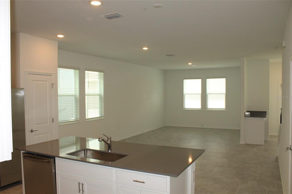 A kitchen island with a sink overlooks an open-concept living area with tile flooring — 4115 CONJUNCTION WAY, APOPKA, FL