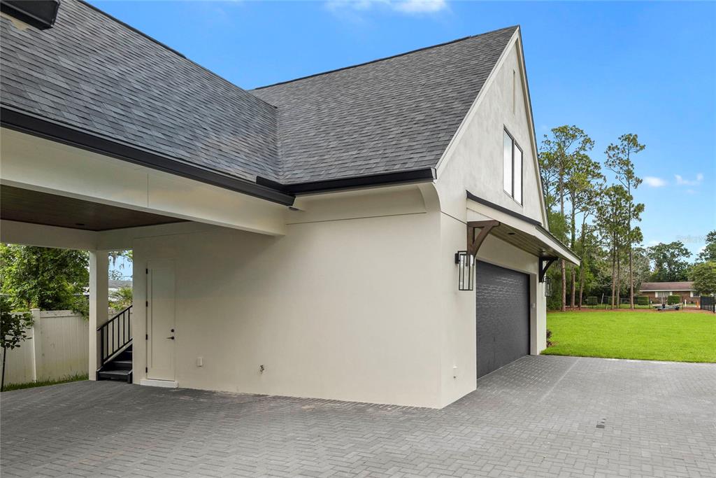 A paved driveway leads to a garage and a covered area with a staircase — 3222 HOLLIDAY AVE, APOPKA, FL