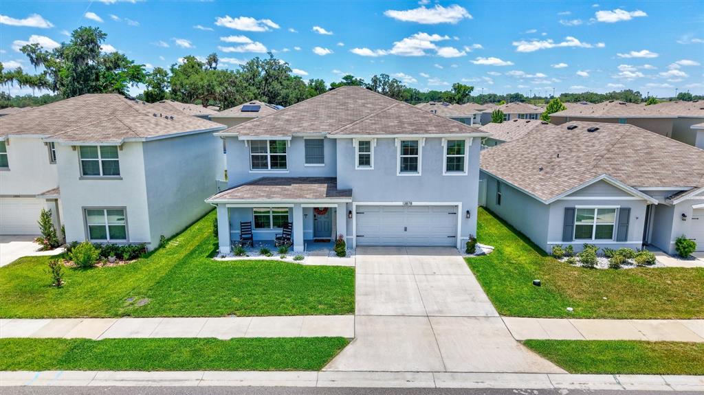 A two-story suburban house with a light blue exterior, a two-car garage, and a lawn — 13878 WINEBERRY DRIVE, DADE CITY, FL