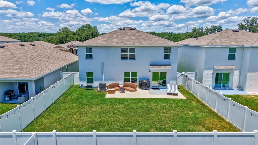 An aerial view shows the backyard of a two-story house with a white fence — 13878 WINEBERRY DRIVE, DADE CITY, FL