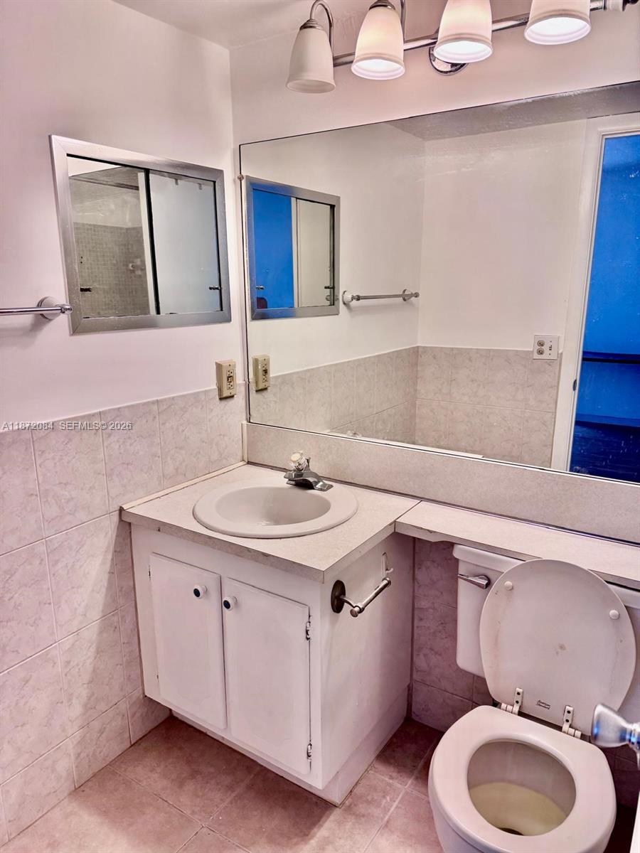A bathroom features a white vanity, a large wall mirror, and a toilet — 19 Newport # A, Deerfield Beach FL 33442, DEERFIELD BEACH, FL