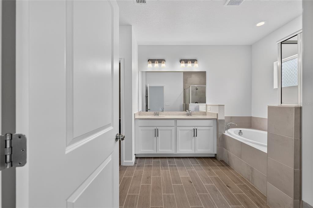 A bathroom features a double vanity with white cabinets, a soaking tub, and tiled flooring — 8846 SW 69TH TERRACE, OCALA, FL