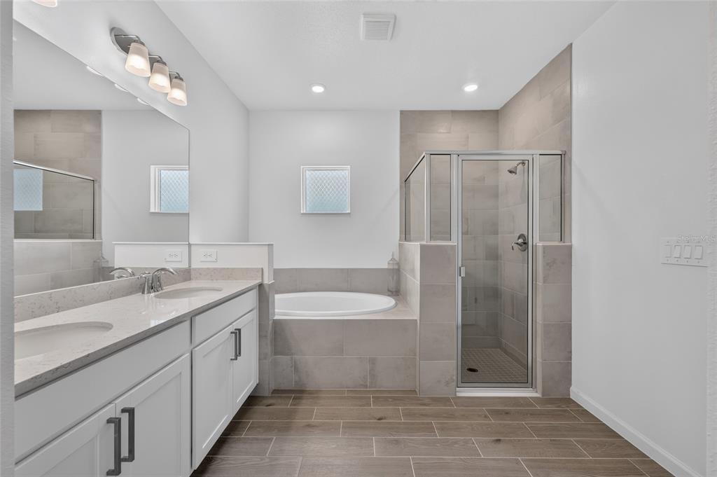 A modern bathroom features a double vanity, a soaking tub, and a glass-enclosed walk-in shower — 8846 SW 69TH TERRACE, OCALA, FL