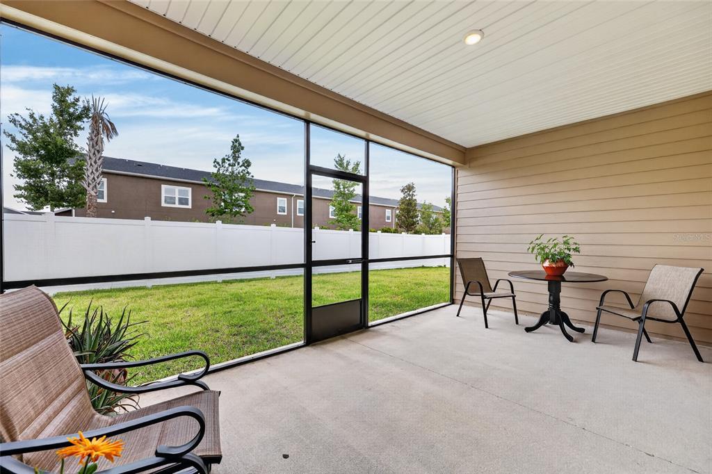 A screened-in concrete patio features outdoor furniture and a view of a fenced backyard — 8846 SW 69TH TERRACE, OCALA, FL