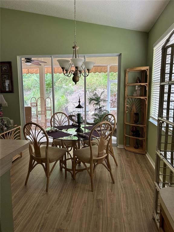 A dining area features a glass-top table, rattan chairs, a chandelier, and a sliding glass door — 2205 CALEDONIAN STREET, CLERMONT, FL