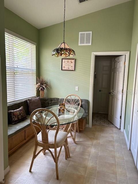 A breakfast nook features a glass-topped table, rattan chairs, a built-in bench, and a pendant light — 2205 CALEDONIAN STREET, CLERMONT, FL