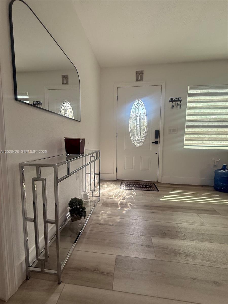 An entryway features a chrome console table, a wall mirror, and light wood-look flooring — 820 N trebol st, Clewiston FL 33440, CLEWISTON, FL