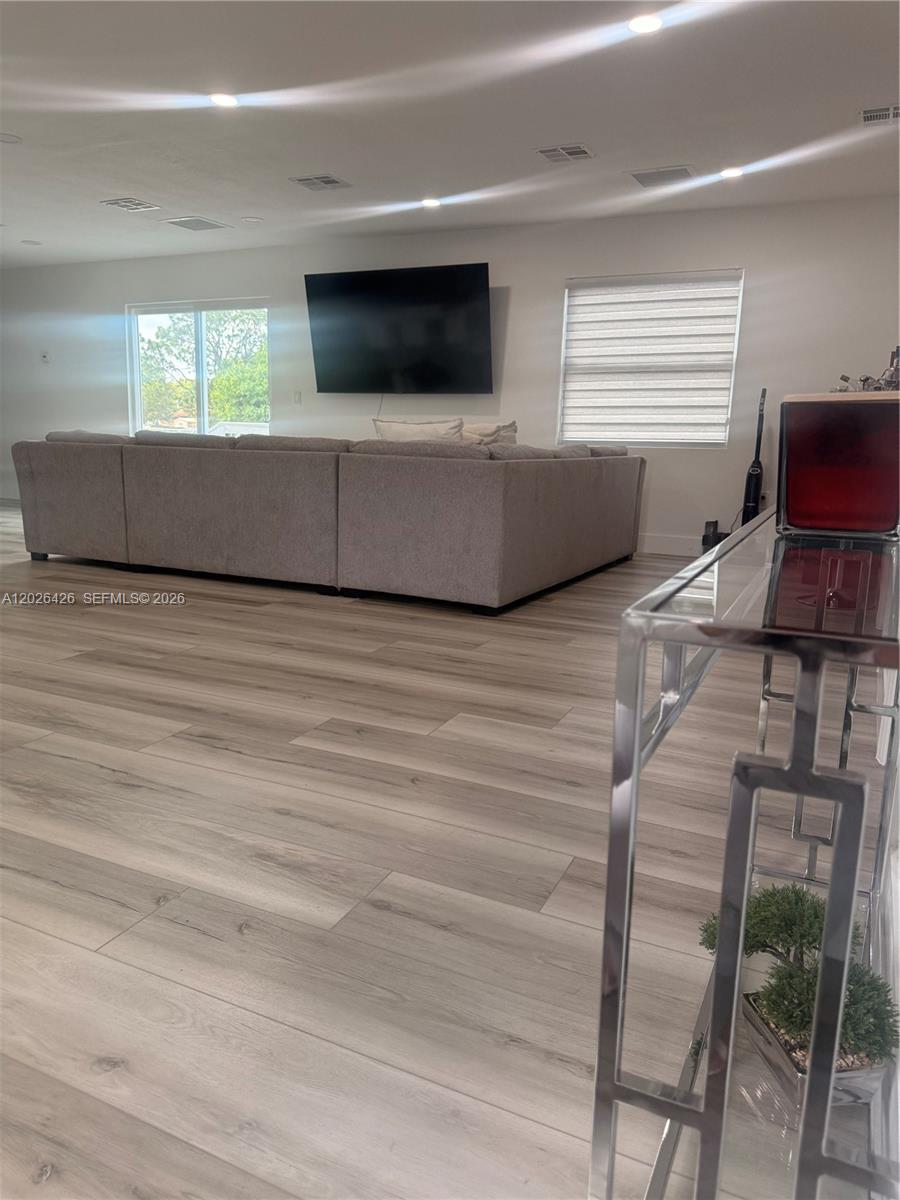 A living room features light wood-look flooring, a large sectional sofa, and a wall-mounted television — 820 N trebol st, Clewiston FL 33440, CLEWISTON, FL