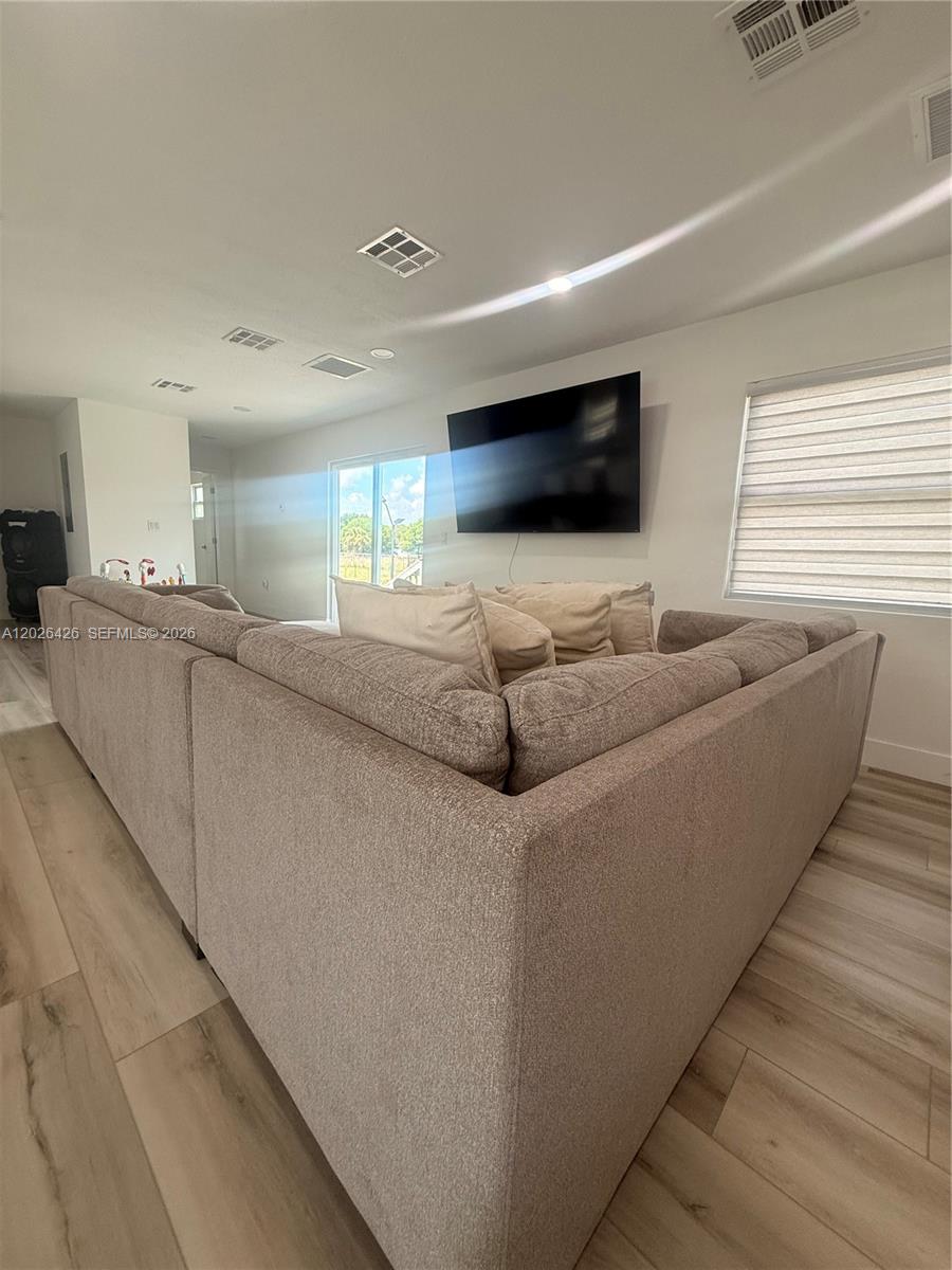 A living room features a large sectional sofa facing a wall-mounted television and window — 820 N trebol st, Clewiston FL 33440, CLEWISTON, FL