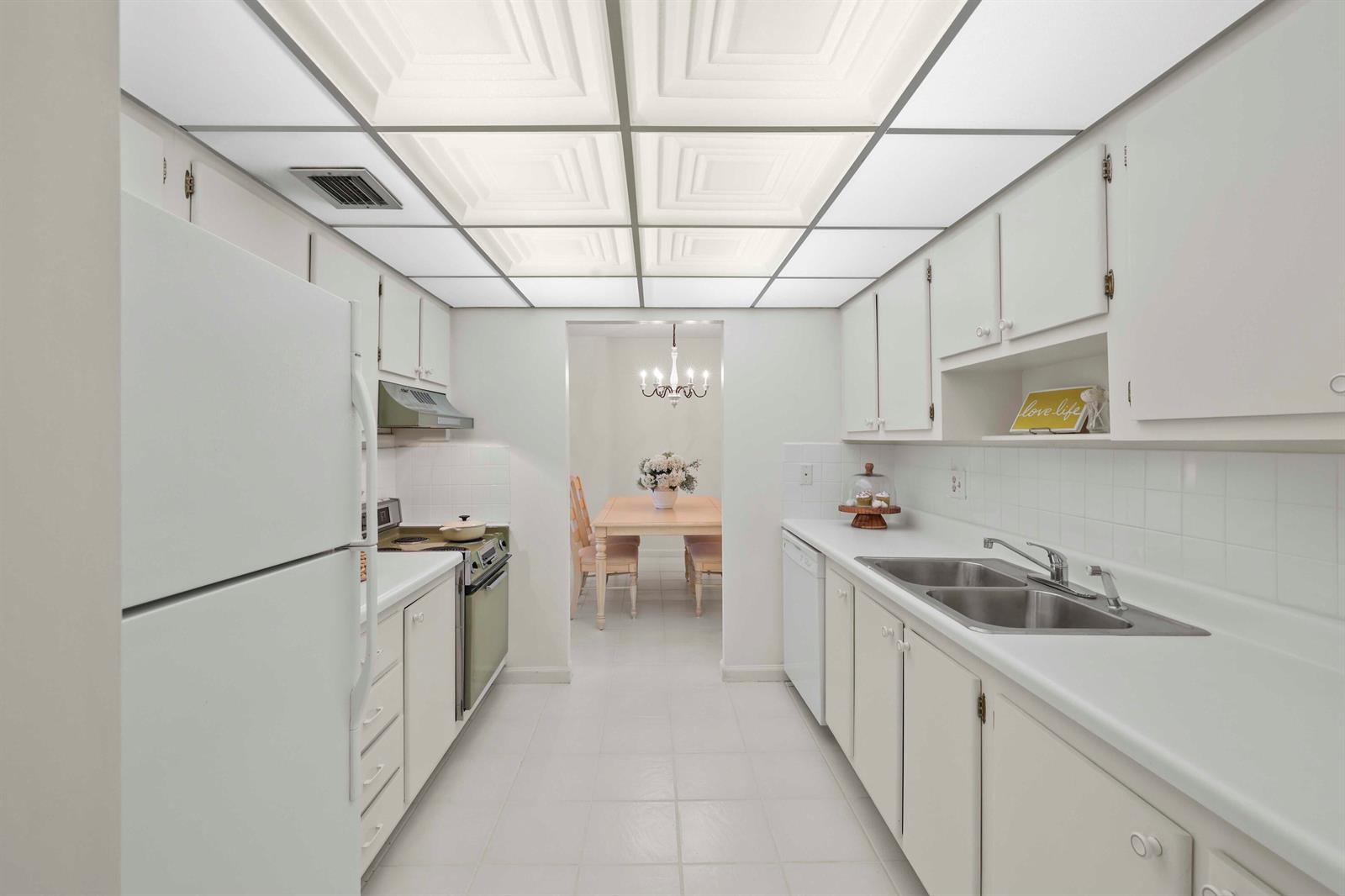 A galley kitchen features white cabinets, white appliances, a tiled floor, and a drop ceiling — 951 De Soto Road # 232, Boca Raton FL 33432, BOCA RATON, FL