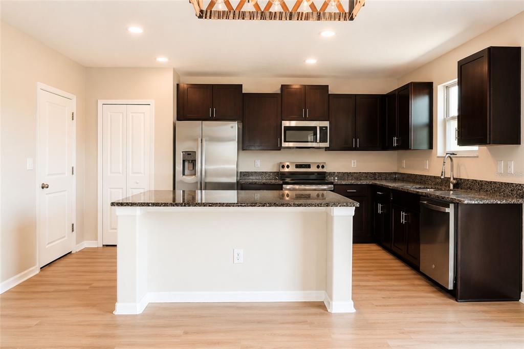 A kitchen with dark wood cabinets, granite countertops, stainless steel appliances, and a central island — 715 CALICO SCALLOP STREET, RUSKIN, FL