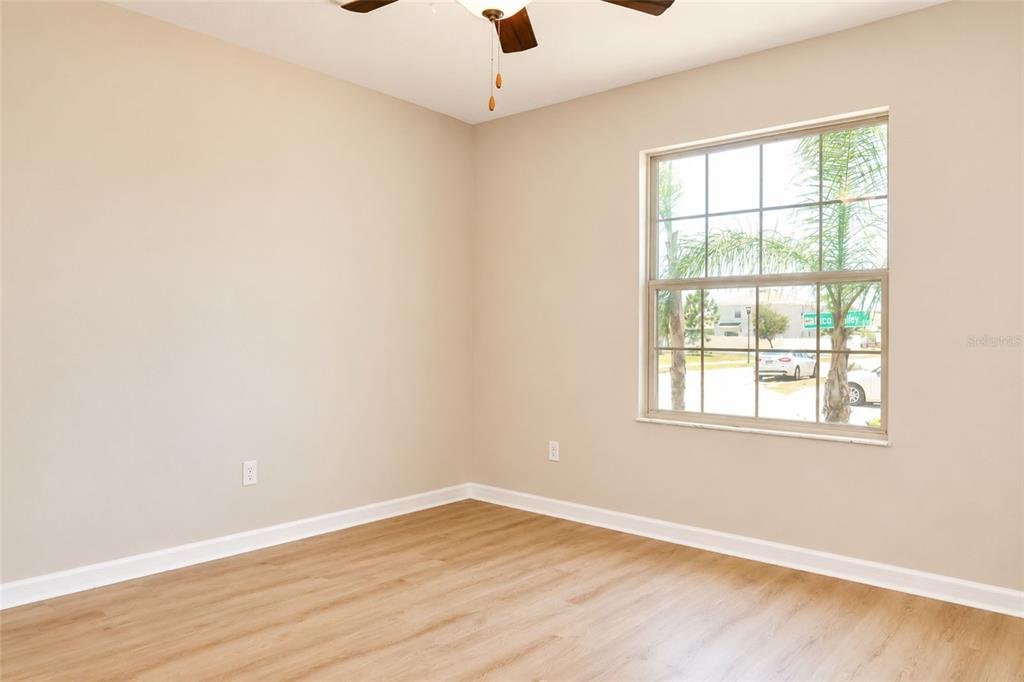An empty room with light-colored walls, wood-look flooring, a ceiling fan, and a large window — 715 CALICO SCALLOP STREET, RUSKIN, FL